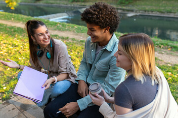 Group of diverse students outside smiling together and studying in park