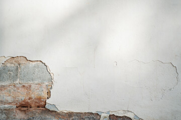 old white wall with chipped away paint and brick detail