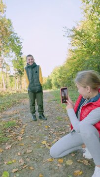 girl photographing boy in autumn forest