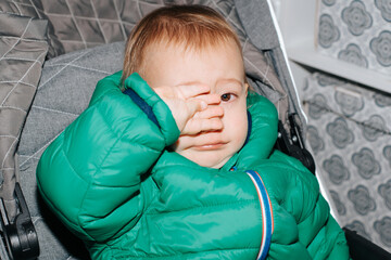 Portrait of crying child. Close-up of little cute boy in jacket wiping away tears, upset, sad,...