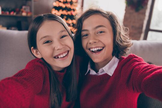 Photo of funny funky brother sister dressed red sweaters recoding noel congratulations smiling indoors room home house