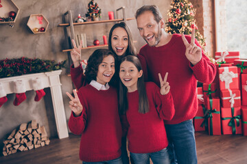 Photo of carefree excited mom dad sister brother smiling hugging showing v-signs enjoying noel time indoors house home room