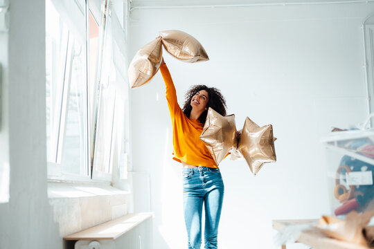 Happy woman holding foil balloons at home