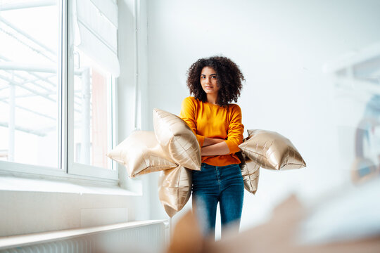 Afro woman holding foil balloons in living room