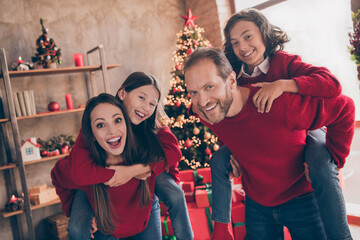 Photo of excited funky mom dad sister brother smiling hugging holding hands arms piggyback enjoying noel spirit indoors house home room