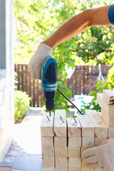 Master cabinetmaker makes wooden furniture with drill, nails, hammer. Handmade in home workshop.