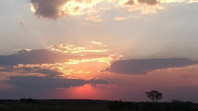 Spectacular African sunset of red yellow and gold through big white clouds over African landscape Aerial video. Kwando River, Mudumu, Caprivi, Namibia