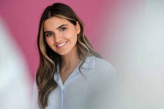 Smiling female business professional with brown hair in front of wall