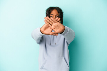 Young african american man isolated on blue background doing a denial gesture