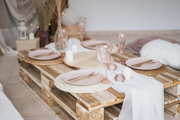 Boho rustic banquet decorated served table for celebration. Birthday party, babyshower, bachelorette party, wedding, luxuary style. White and pink dishes, candels, textyle.
