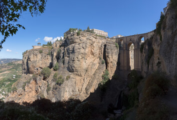 Fototapeta na wymiar View at the New Bridge above the gauge and the natural geological phenomenon, erosion cliffs around the city, a iconic and touristic travel destination on Ronda city