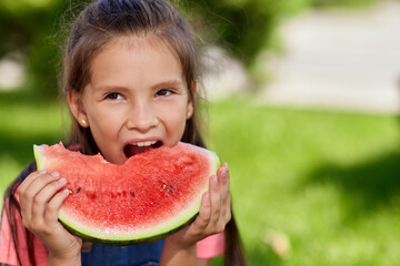 child girl eats a watermelon in sunny day