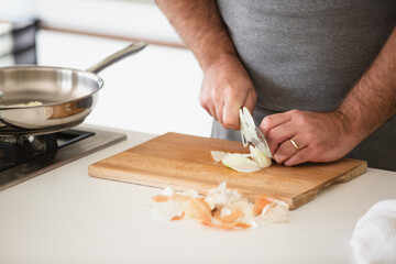 Obraz na płótnie Canvas Man cutting vegetables on wooden desk in home kitchen