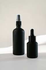 Black cosmetic bottles on a background flooded with sunlight.
