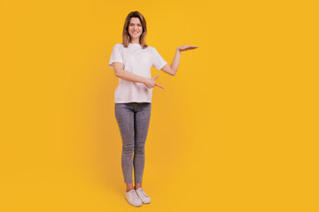 Photo of positive lady hand measure size empty space wear casual t-shirt jeans on yellow background