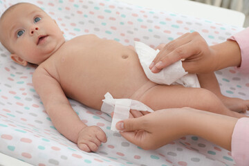 Mother changing her baby's diaper on table