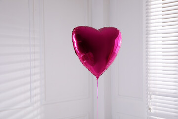 Festive heart shaped balloon in light room