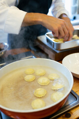The chef cooks ravioli in boiling water. Italian cooking technique.