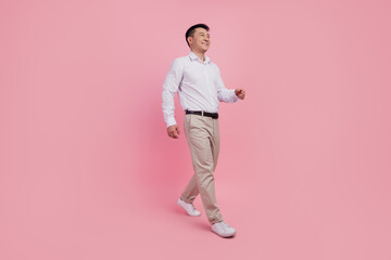 Fototapeta na wymiar Full length profile side photo of young asian man go walk step look empty space isolated over pink color background
