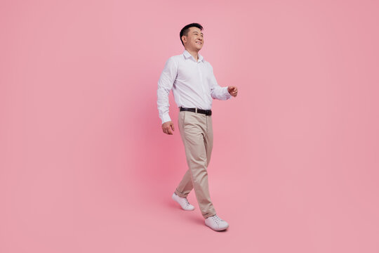 Full Length Profile Side Photo Of Young Asian Man Go Walk Step Look Empty Space Isolated Over Pink Color Background