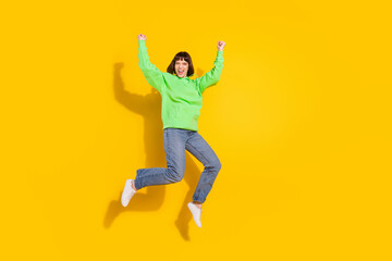 Full length photo of happy charming attractive woman jump up winner isolated on shine yellow color background