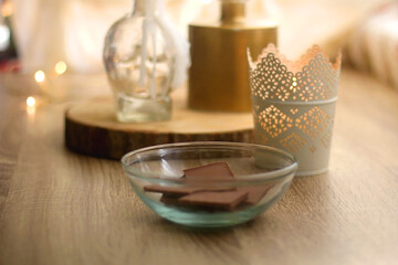 Bowl of chocolate, candles and vase with flowers on the table. Selective focus.