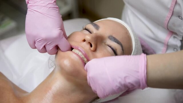 The salon specialist makes the girl a cheek massag