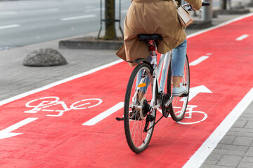 traffic, city transport and people concept - woman cycling along red bike lane with signs of...