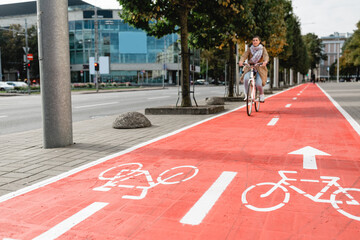 traffic, city transport and people concept - woman cycling along red bike lane with signs of...