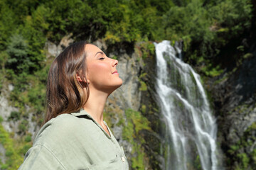 Woman relaxing breathing fresh air in a waterfall