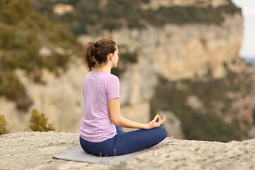 Fototapeta na wymiar Woman alone doing yoga in a cliff
