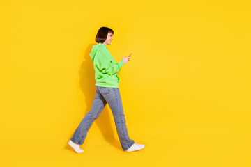 Fototapeta na wymiar Full length body size profile side view of nice cheery girl going using gadget isolated over bright yellow color background