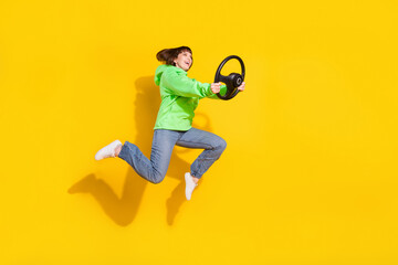 Fototapeta na wymiar Full length body size view of attractive cheery girl jumping holding steering wheel having fun isolated over bright yellow color background