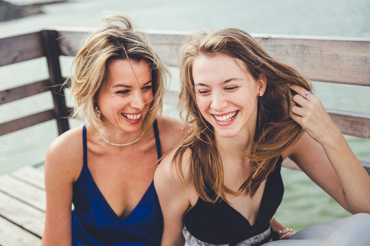 Happy mother and daughter sitting on jetty