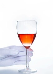Sommelier's hand in a white glove takes a glass of red wine on a white background