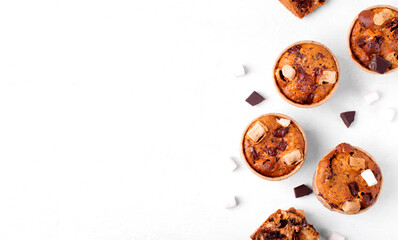 Muffin with banana, marshmallow, chocolate and cracker crumbs in craft paper cups on the white table. Variation of Smore dessert. Copy space