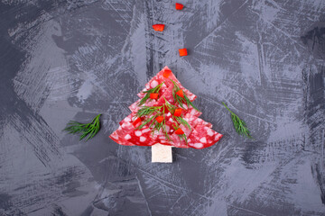 Canape, Christmas tree, with salami on white bread topped with dill and pepper on the gray table. Top view. Festive appetizer. New Year table setting