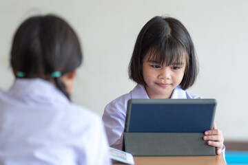 Asian children student friends back to school and study together using digital tablet and write on notebook at school afet Covid-19 lockdown. Back to School Concept Stock Photo