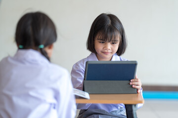 Asian children student friends back to school and study together using digital tablet and write on notebook at school afet Covid-19 lockdown. Back to School Concept Stock Photo