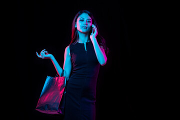 Portrait of young woman in neon light on dark backgound. Human emotions, black friday, cyber monday, purchases, sales, finance concept.
