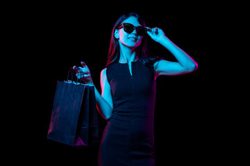 Portrait of young woman in neon light on dark backgound. Human emotions, black friday, cyber...