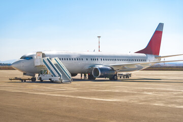 Fototapeta na wymiar Airplane is parked near gate of airport terminal