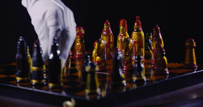 Chessboard close-up. Two unrecognizable persons in white cloth gloves play chess, move pieces and make moves