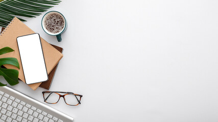 Smartphone mock up screen note keyboard glasses palm leaves on white work space desk. Mobile phone on modern office desk workspace. Long web banner with copy space.