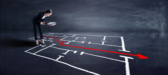 Attractive young businesswoman with magnifier looking at maze and arrow sketch on chalkboard background. Solution, direction, way and challenge concept.