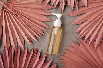 Natural beauty product background with a bottle and dried pink palm leaves