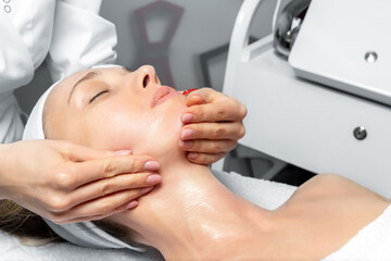 Close-up beautician doctor hand making anti-age procedure, mask and peeling for young attractive...