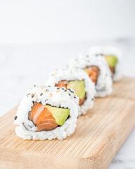 Salmon and avocado sushi pieces on a wooden table