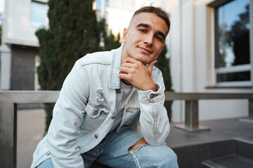 Young casual man sitting on stairs alone on street