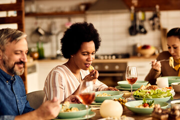 African American woman enjoys in lunch with her friends in dining room at home.